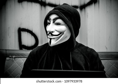 Paris - France - 19 May 2018 - portrait of man with Vendetta mask and coumputer in abandoned  factory  on vintage armchair . This mask is a well-known symbol for the online hacktivist group Anonymous