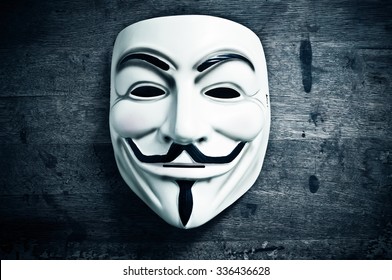Paris - France - 8 November 2015 - Vendetta mask on wooden background . This mask is a well-known symbol for the online hacktivist group Anonymous
