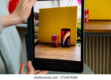 Paris, France - Apr 16, 2020: Woman Looking On Apple Computers Internet Website On IPad Pro Tablet Comparing New IPhone SE With AR Augmented Reality With Coca Cola Can