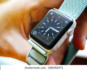 PARIS, FRANCE - APR 24, 2018: New Apple Watch Series 3 smartwatch personal wearable device in male hand with the new 42mm Marine Green Sport Loop show the classic watch face