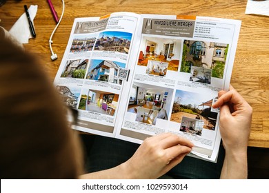 PARIS, FRANCE - APR 26, 2017: View From Above Of Woman Reading Houses And Apartments Real Estate Catalogue With Properties For Rent And Buy In France, Alsace Maisons Alsace