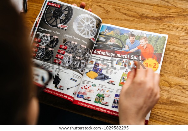 PARIS, FRANCE -\
APR 26, 2017: Elevated view woman reading A.T.U Auto-Teile-Unger\
German automotive services advertising leaflet with accessories and\
car care products