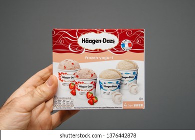 Paris, France - Apr 6, 2019: Man Hand Holding Against Gray Background Package Of Haagen-Dazs Frozen Yogurt Ice Cream With Diffrent Tastes And New Collection