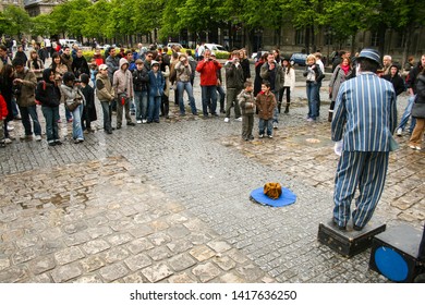 Paris, France - April 13 2008 - A Crowd Including Two Young Boys Watching A Busker Dressed As A Mime Performing In Front Of Notre Dame Cathedral.  