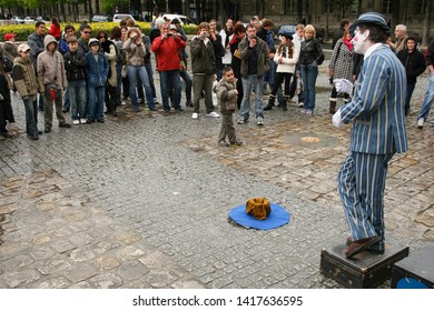 Paris, France - April 13 2008 - A Crowd With A Young Boy In Front Watching A Busker Dressed As A Mime Performing In Front Of Notre Dame Cathedral.  