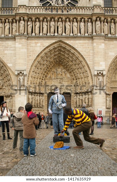 Paris, France - April 13 2008 - A spectator\
makes a donation to a busker, who is performing dressed as a mime\
outside of Notre Dame\
Cathedral.