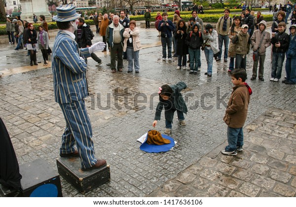 Paris,\
France - April 13 2008 - A sweet young child spectator makes a\
donation to a busker, who is performing dressed as a mime outside\
of Notre Dame Cathedral.  Image has copy\
space.