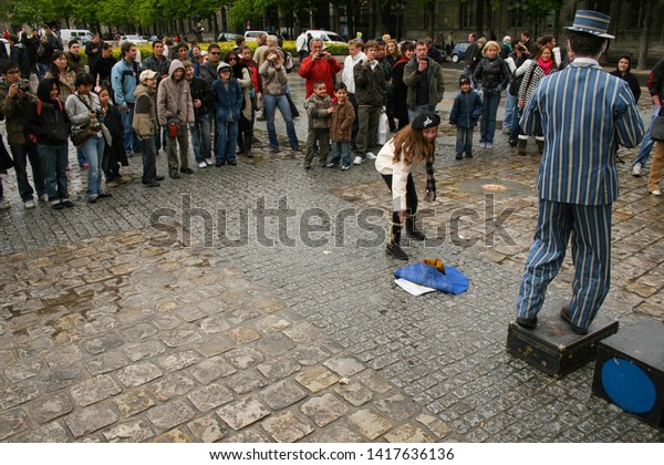 Paris, France - April\
13 2008 - A female spectator makes a donation to a busker, who is\
performing dressed as a mime outside of Notre Dame Cathedral. \
Image has copy space.