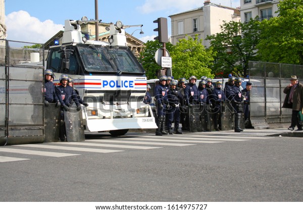 Paris, France - April 15 2008 - A man waling past\
a group of police officers dressed in uniforms and wearing riot\
gear, in front on a large police truck at a student protest.  Image\
has copy space.