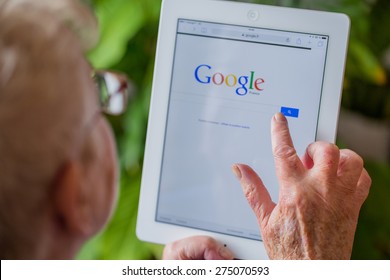 Paris, France - April 27, 2015: Senior Woman Using Tablet With Google Search Home Page On A Ipad Screen