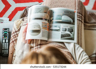 PARIS, FRANCE - AUGUST 24, 2014: View From Above Of Woman Reading IKEA Catalogue Before Buying Bedding And Bedroom Furniture For Her New House. 