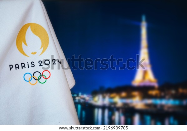 PARIS, FRANCE, AUGUST 8. 2022: Summer olympic game\
Paris 2024 black background. Official logo of SOG 2024 in Paris on\
white blanket with dark City in night. Black edit space, sport\
event