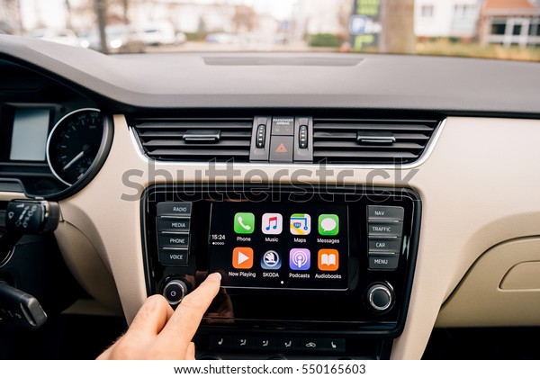 PARIS, FRANCE - DEC 13, 2016: Man pressing home\
button on the Apple CarPlay main screen in modern car dashboard.\
CarPlay is an Apple standard that enables a car radio to be a\
controller for an\
iPhone.