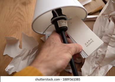 Paris, France - Dec 13, 2020: POV Male Hand Holding Paper Tag Of A Zara Home Table Elegant Lamp With Logotype Of The Renowned Inditex Brand