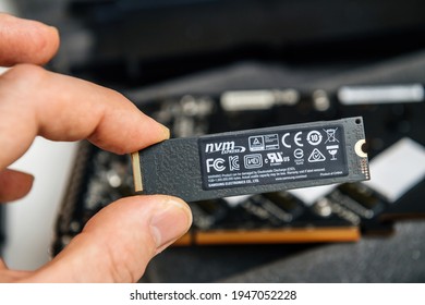 PAris, France - Dec 20, 2020: Male hand holding New NVME ssd fast computer disk near NVME raid device pcie card with multiple certification marks and Samsung Electronics Product of China
