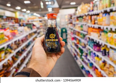 Paris, France - Dec 27, 2017: Man Hand POV Personal Perspective Holding Kikkoman Soja Sauce In Modern Supermarket With Multiple Product On The Shelves