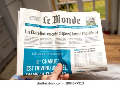 Paris, France - Dec 9 2020: POV Male Hand Holding LE Monde French Newspaper With Title About United States And COVID-19 Vaccine