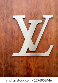 Paris, France - December, 29, 2018: Louis Vuitton LV brushed chrome logo on dark grained wood interior wall
