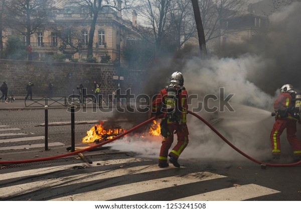 Paris, FRANCE - Decembrer 8 2018 : Firefighters\
try to put out a car fire during the riots of the Yellows vests\
\