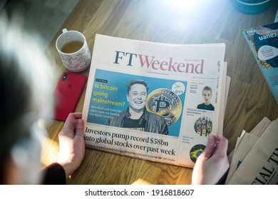 Paris, France - FEb 13, 2021: POV business woman reading Financial Times newspaper on kitchen counter with Elon Musk headline smiling and text Is bitcoin going mainstream