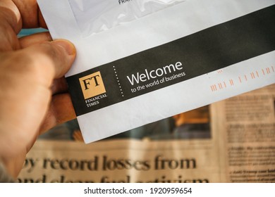 Paris, France - FEb 13, 2021: POV Male Hand Holding Letter Correspondence From Financial Times Newspaper With Welcome The The World Of Business Inscription