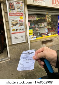 Paris, France - Feb 18, 2020: Senior Male Hand Holding Cane And Lottery Tickets For Lotto And Euromillions My Millions With Winning Numbers In Front Of Tobacco Lottery Press Kiosk