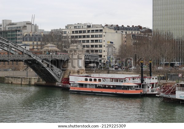 Paris, France - February the 4th 2022\
: winter day in paris, view of the seine with a bateau-mouche, the\
austerlitz viaduct, buildings and cars in\
circulation
