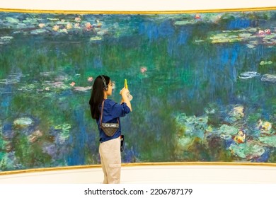 Paris, France - Friday 29th July 2022: Monets Water Lillys With Lady Photographing With Cell Phone In LOrangerie Art Gallery In Paris. High Quality Photo