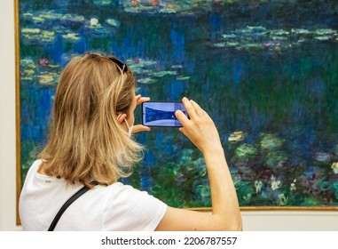 Paris, France - Friday 29th July 2022: Woman Photographing Monet's Water Lillys With Cell Phone In LOrangerie Art Gallery. High Quality Photo