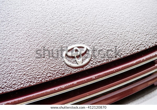 PARIS, FRANCE - JAN 20, 2016: Toyota logotype\
covered with snow flakes during cold period on Paris streets.\
Toyota Motor Corporation is a Japanese automotive manufacturer\
headquartered in Japan