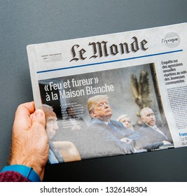 Paris, France - Jan 8, 2018: Man Holding Le Monde Newspaper With Donald Trump And Title Fire And Fury At The White House Against Cold Background