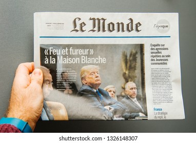 Paris, France - Jan 8, 2018: Man Holding Le Monde Newspaper With Donald Trump And Title Fire And Fury At The White House Against Warm Gray Background