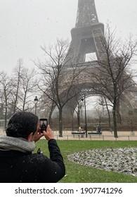 Paris, France, January 16, 2021 - People photographing Eiffel tower while it snows, winter
