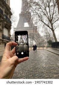 Paris, France, January 16, 2021 - People photographing Eiffel tower while it snows, winter