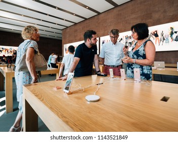 PARIS, FRANCE - JUL 16, 2018: Modern Apple Mac Store Main Hall With Genius Employee Explaining To Couple About IPhone X