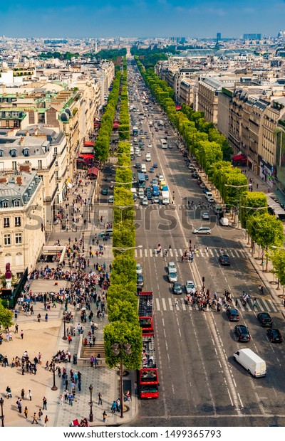 Paris, France - JUL 2011: Great aerial\
portrait view of the famous Avenue des Champs-Élysées on a nice day\
with a blue sky at the horizon. People walking along the shops or\
crossing at the\
crosswalk.