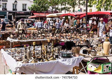 Paris, France - Jule 09, 2017: People Choosing Rare And Used Books, Wooden Masks And Figures Of African Culture At The Historic Flea Aligre Market (Marche D'Aligre) In The Bastille District.