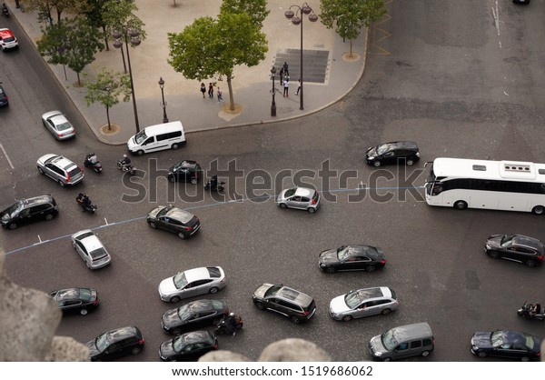 Paris, France - July\
2019 - Traffic at the foot of Arc de Triomphe, around the\
roundabout of Place de l\'Etoile, with cars, scooters, motos, vans\
and a coach, seen from\
above