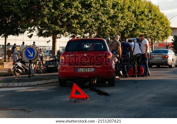 PARIS, FRANCE - July, 2021: Car accident on city\
road at intersection of magasin GiFi. People trying to get people\
out of the overturned\
car.