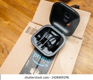 Paris, France - Jun 17, 2019: wooden table with Amazon Prime cardboard parcel and Powerbeats Pro Beats by Dr Dre wireless high-performance earphones waterproof and workout professional headphones