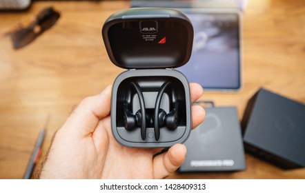 Paris, France - Jun 17, 2019: Man hand holding Powerbeats Pro Beats by Dr Dre wireless high-performance earphones waterproof and workout professional headphones in their charging case - view from