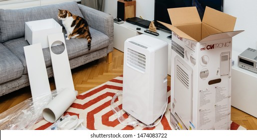 Paris, France - Jun 23, 2019: Curious Cat Inspecting The Unboxing Installing New Portable Air Conditioner Unit AC During Hot Summer In Living Room Clatronic Model