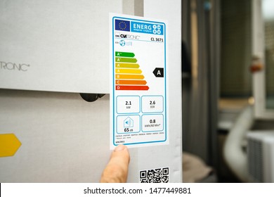 Paris, France - Jun 23, 2019: Young Man Reading Energy Label Before Installing New Portable Air Conditioner Unit AC During Hot Summer In His Living Room Clatronic