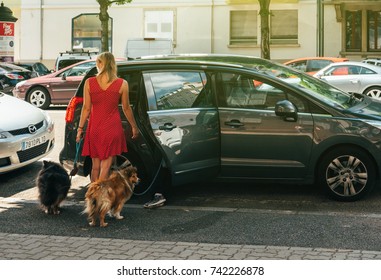 PARIS, FRANCE - JUN 24, 2017: Young Woman Opening Rear Door Of A Peugeot Minivan After Walking A Couple Of Funny Shetland Sheepdogs On A French Street