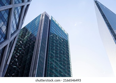 Paris, France - June 12, 2022: Glass facades of a skyscraper on a bright sunny day with sunbeams in the blue sky. A modern building in the La Defense business district of Paris. Economy, finance, busi