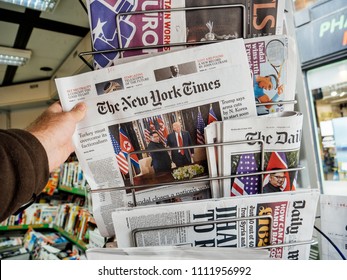 PARIS, FRANCE - JUNE 13, 2018: Man Buying The New York Times Newspaper At Press Kiosk Showing On Cover  U.S. President Donald Trump Meeting North Korean Leader Kim Jong-un In Singapore 