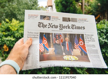 PARIS, FRANCE - JUNE 13, 2018: Man Reading The New York Times Newspaper  Showing On Cover  U.S. President Donald Trump Meeting North Korean Leader Kim Jong-un In Singapore 