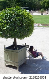 
PARIS, FRANCE - June 16, 2022: girl resting on a chair in the Luxembourg Gardens in Paris