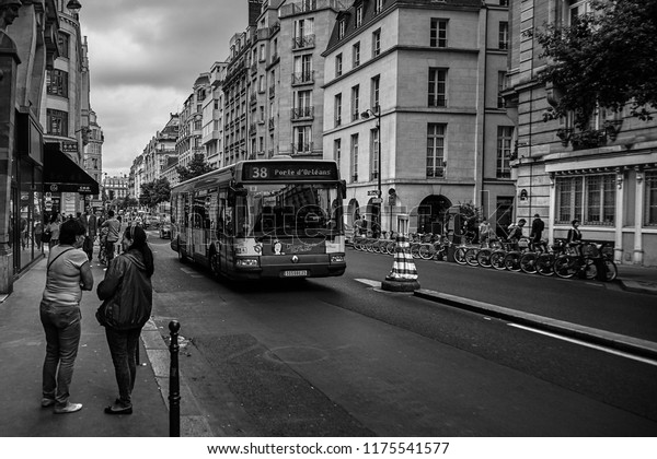 Paris,\
France - June 18, 2015: Two women talking on the sidewalk. The bus\
is on the road. Public transportation of the\
city