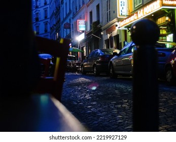 Paris France - June 22 2009; Street Level In Montmartre, Dark European City Street With Vehicles Parked And Illuminated Restaurant Signs